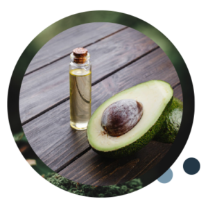 Halbierte Avocado mit der angeschnittenen Seite nach oben, neben einem kleinen, transparenten Fläschchen Avocado-Öl.