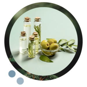 Einige kleine Flaschen mit Olivenlöl, daneben ein Glasschälchen mit grünen Oliven und ein Olivenzweig.